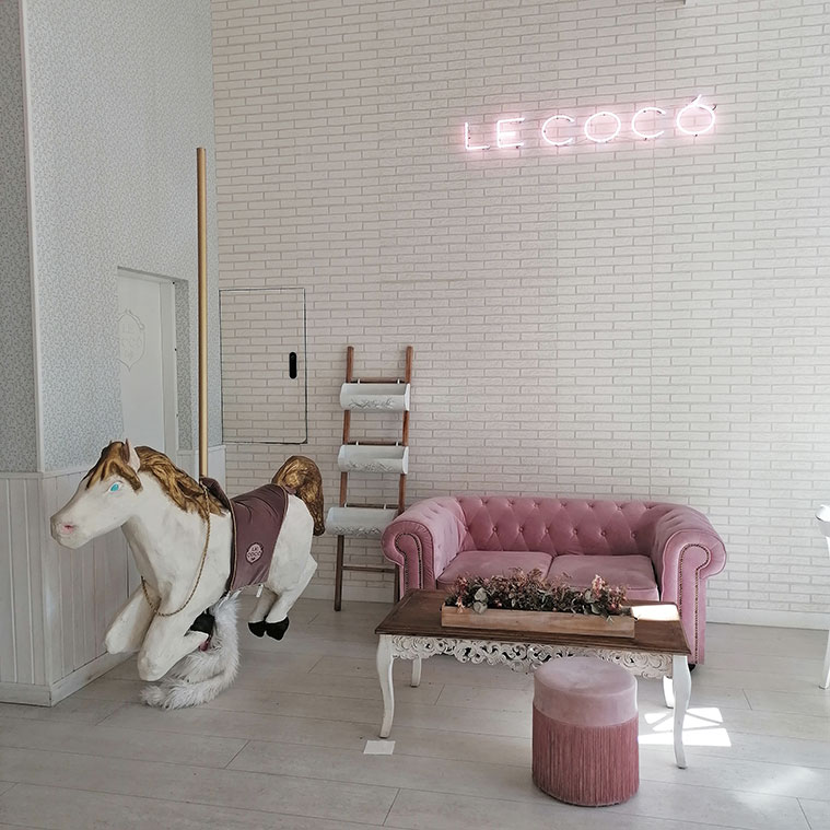 Un caballito de tiovivo y un sofá de terciopelo rosa forman parte de la decoración de Le Cocó Café