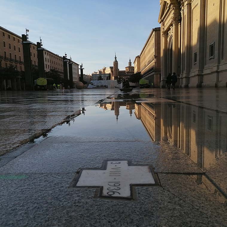 Una pequeña cruz sobre el pavimento muestra el lugar exacto de la plaza del Pilar en el que cayó una bomba el 3 de agosto del año 1936