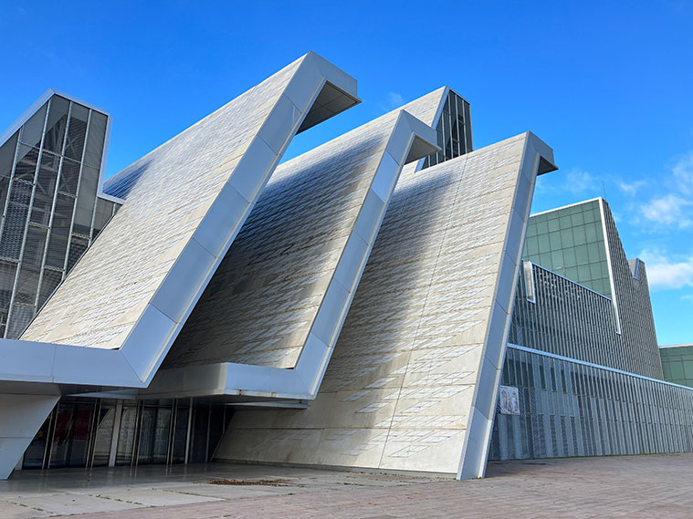 El perfil del Palacio de Congresos de Zaragoza presenta una forma quebrada y variable, con ascensos y descensos, estableciendo un diálogo con los diversos espacios que se encuentran en su interior