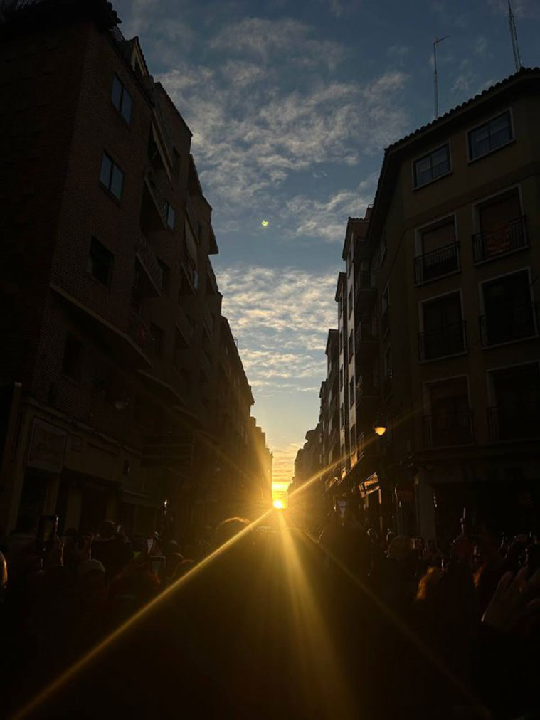 Momento en el que el sol ha asomado en el horizonte de la calle Mayor de Zaragoza frente a decenas de personas allí congregadas para ver el evento