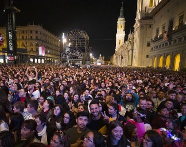 Escenario iluminado en la Plaza del Pilar de Zaragoza con público disfrutando de un concierto gratuito de las Fiestas del Pilar